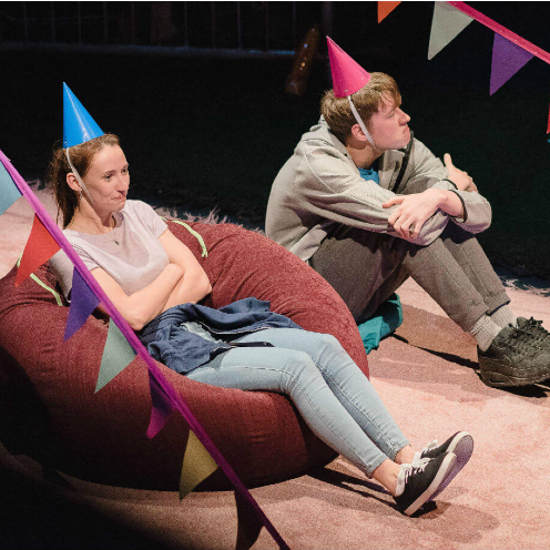 two young people sitting on bean bags wearing party hats